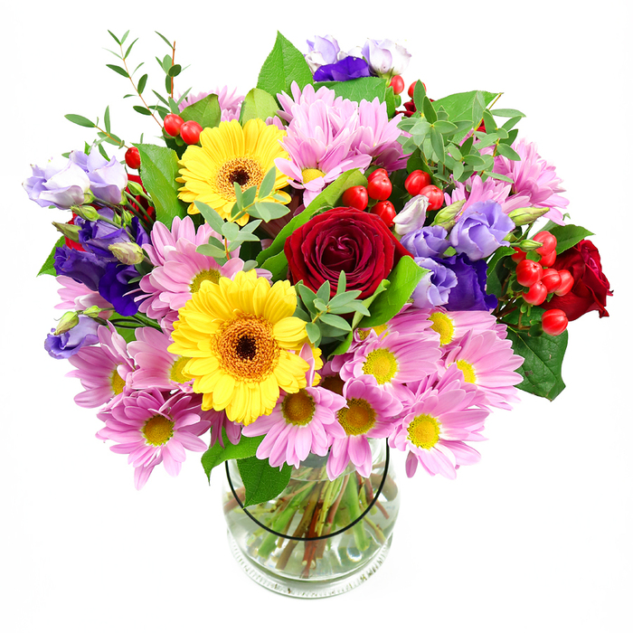 A vibrant mixed bouquet is arranged with care in a clear glass vase, its colours standing out vividly against a white background, much like a splash of street art along the walls near Cambridge Heath station. At the heart of the design, deep red roses open in lush, velvety spirals, providing a rich centre of romance and warmth. Around them, bold yellow gerbera daisies with their brown-orange centres bring a modern, graphic feel, their simple, round faces radiating brightness and good cheer. Soft pink daisies or chrysanthemums cluster generously around these focal blooms, their many fine petals creating a gentle haze of colour, each small yellow centre glinting like a drop of afternoon sun. Intertwined among the pink flowers, lisianthus in shades of purple and lavender curve and tuck into the spaces between, their bell-shaped blossoms adding a cooler, more contemplative tone that balances the vivid warmth of the reds and yellows. Here and there, smooth, glossy hypericum berries in bright red peep out from between leaves, contributing a playful texture and a slightly festive air, as though ready to grace a celebration in a Cambridge Heath loft or gallery. The bouquet is wrapped visually by generous greenery: deep green, broad leaves provide structure, while slender, softer shoots in lighter tones add motion and a sense of being freshly cut. Through the transparent vase, the carefully cut stems are visible, aligned in a clean, fan-like pattern in clear water, giving a glimpse of the florist's precise work. Overall, the bouquet conveys joy, creativity, and warmth, ideal for birthdays, house-warmings, or simply bringing an uplifting touch of nature into a Cambridge Heath home or workspace, where its fragrance and colour can soften the industrial edges of the city.